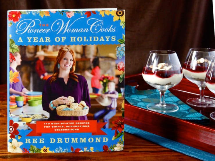 A picture of cherry cheesecake shooters next to Ree Drummond's cookbook The Pioneer Woman Cooks A Year Of Holidays. 