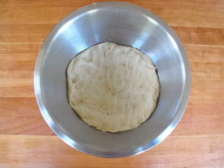 Challah dough punched down in a bowl.