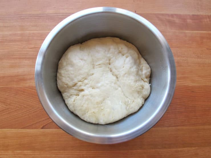 Challah dough punched down in a bowl.