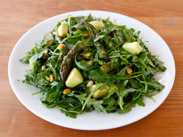 Roasted Asparagus, Avocado and Arugula Salad served on a white plate on top of a wooden table
