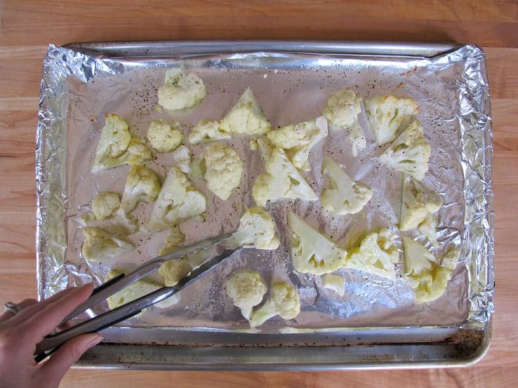 Turning florets on baking sheet with tongs.