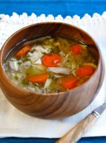 Horizontal shot of Rotisserie Chicken Rice Soup on a brown bowl and a spoon on top of a white cloth.