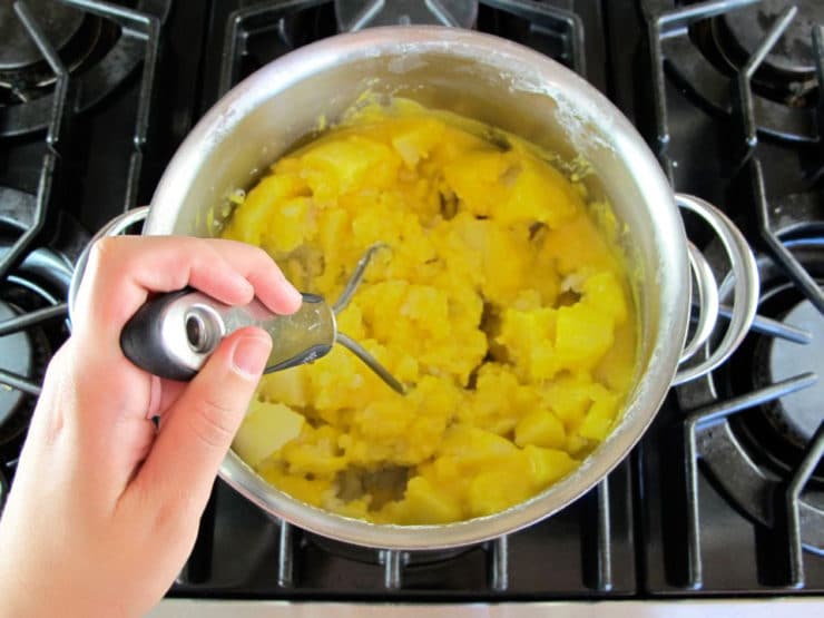 Mashing potatoes in a stockpot.