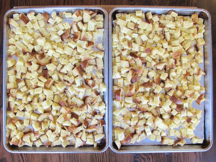 Cubed challah spread out on baking sheets to dry.