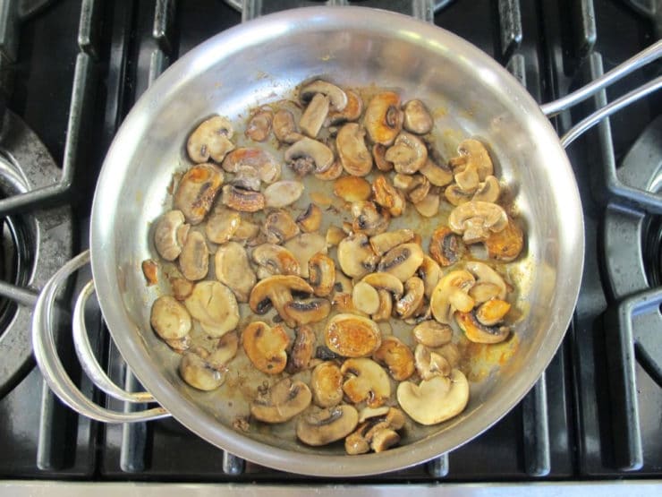 Sliced mushrooms browning in a skillet.