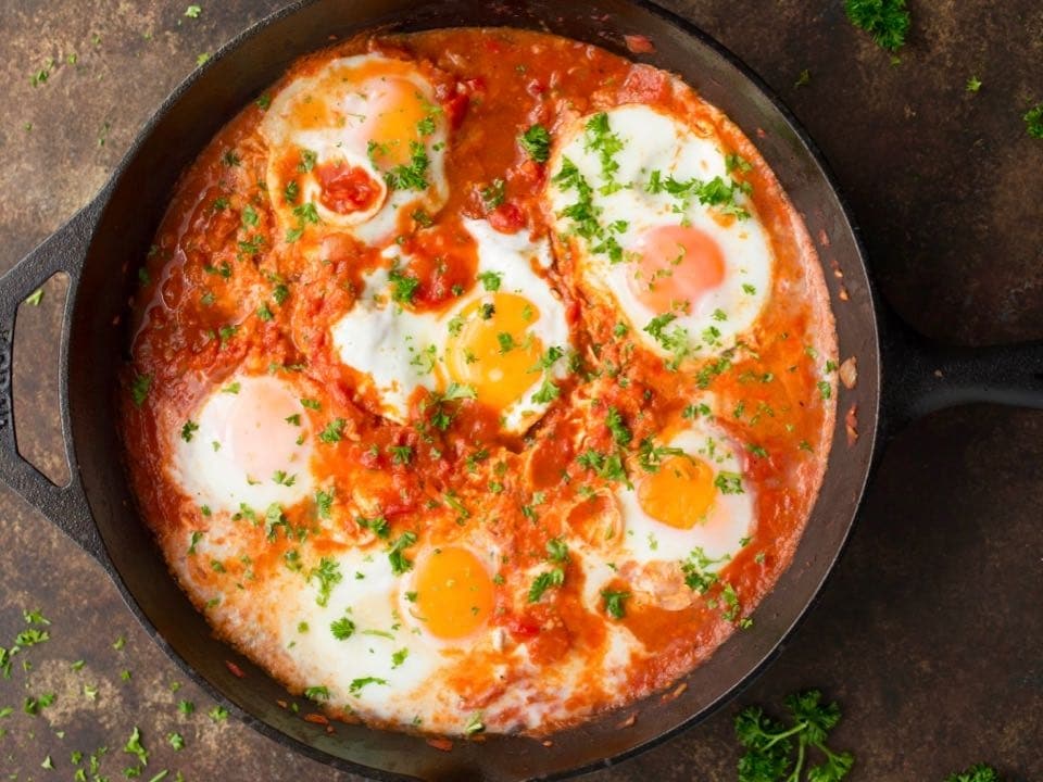 Horizontal shot of cast iron pan filled with Shakshuka.