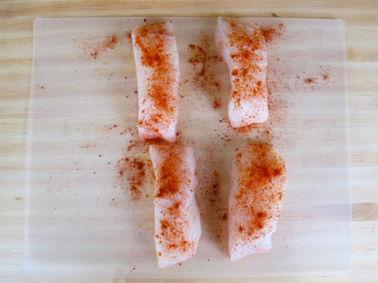 Season fish fillets on a cutting board.