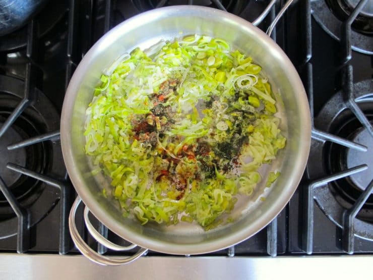 Spices added to leek soup in a stockpot.