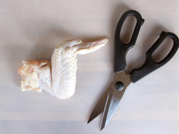 Separating the two chicken wing parts.