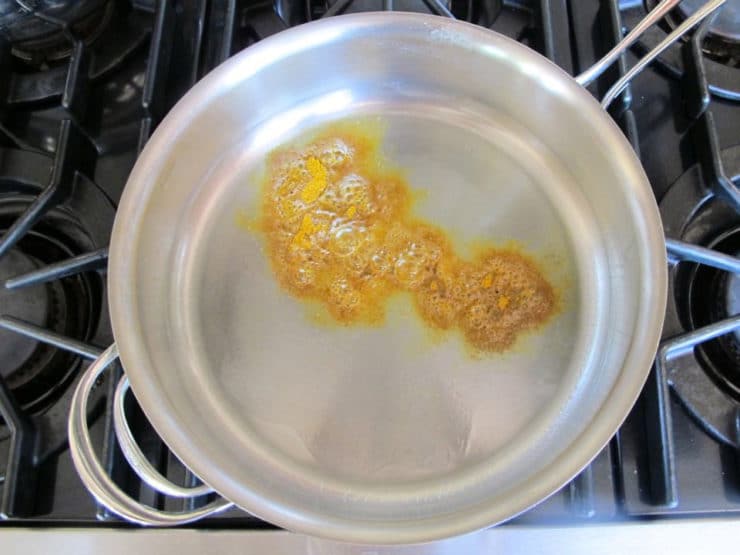 Spices heating in oil in a skillet.