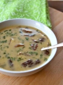 A bowl of coconut soup with red curry paste, coconut milk, and chicken, served with spoon.