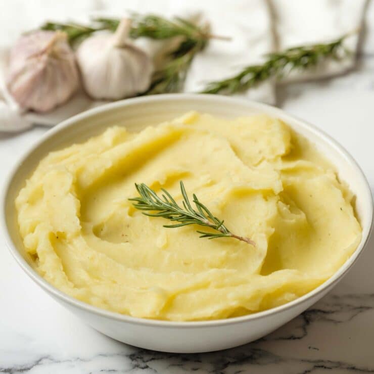 Dish of olive oil mashed potatoes garnished with fresh rosemary.