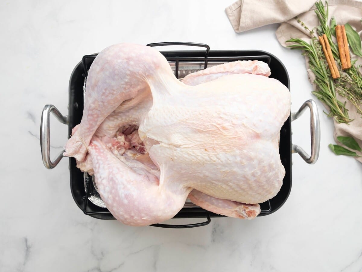 Overhead shot of a raw turkey sitting on top of a roasting pan rack.
