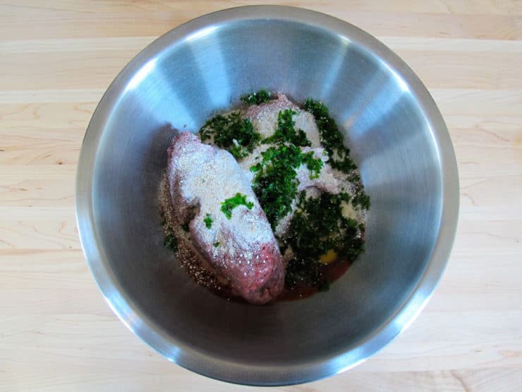 Ground meat and seasoning in a mixing bowl.