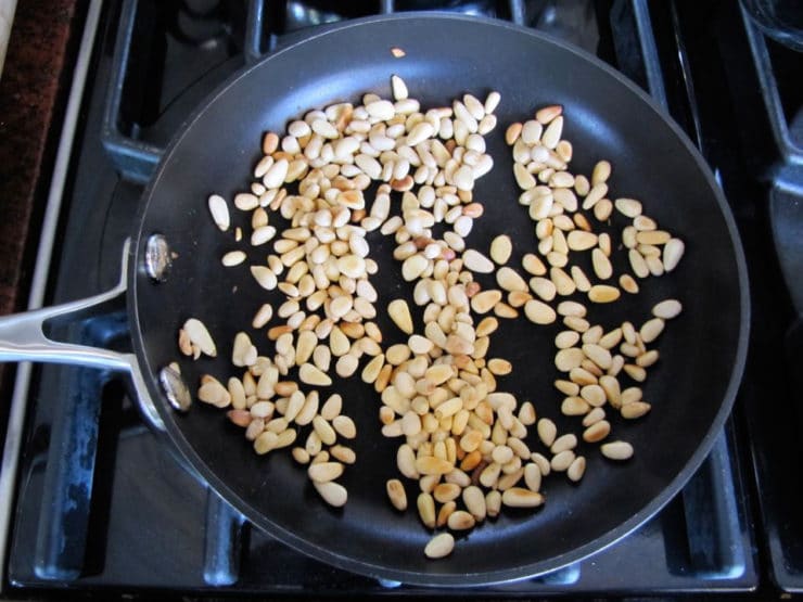 Pine nuts dry toasting in a skillet.