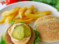 Black Eyed Pea Burger topped with a mayonnaise and pickles surrounded with fries, burger bun, tomatoes, and lettuce
