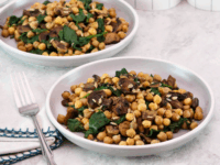 Chickpea, Spinach and Mushroom Sauté Pinterest Pin - two servings of sautéed chickpeas with spinach mushrooms on a white plate. A pair of fork, linen napkin, and white canister in the background.