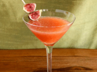 A Fig and Honey Cocktail with a fig garnish placed on a wooden table, creating a visually appealing drink