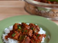 Close-up of Hungarian Beef Goulash served on top of a rice in a sage green plate with fork on the right side Pinterest Pin at ToriAvey.com