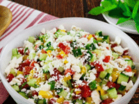 A bowl of Israeli salad with cucumber, tomato, feta cheese, and mint served on a white bowl. Pinterest Pin at ToriAvey.com