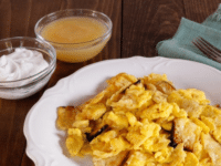 Matzah with scrambled eggs on a plate with applesauce and sour cream on the side