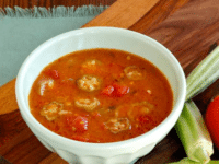 Okra soup served on a white bowl with fresh okra and tomato on side of the bowl Pinterest at ToriAvey.com