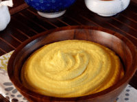 Peanut Hummus served in a brown bowl with a bowl of peanuts and spies at the back.