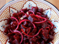 Close-up of a chopped Roasted Beet and Red Onion Salad served in a plate with design on top of a wooden table