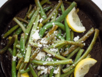 Skillet Seared Green Beans served on a skillet topped with lemon slices and Cotija Cheese
