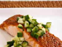 Grilled salmon topped with green apple salad salsa served on a white plate