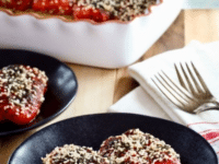 Two Red peppers with sesame seeds and stuffed with goat cheese on a black plate