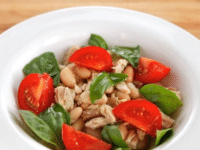 Top view of Tuna Salad Caprese made with beans, tomatoes, tuna flakes, and basil leaves served on a white plate