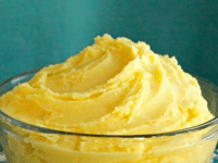 A bowl of saffron mashed potatoes, with a vibrant yellow butter, placed on a table. Pinterest Pin at toriAvey.com