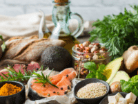 Close-up of different ingredients from nuts, beans, herbs, salmon, avocado, bread, and olive oil arranged altogether in a table